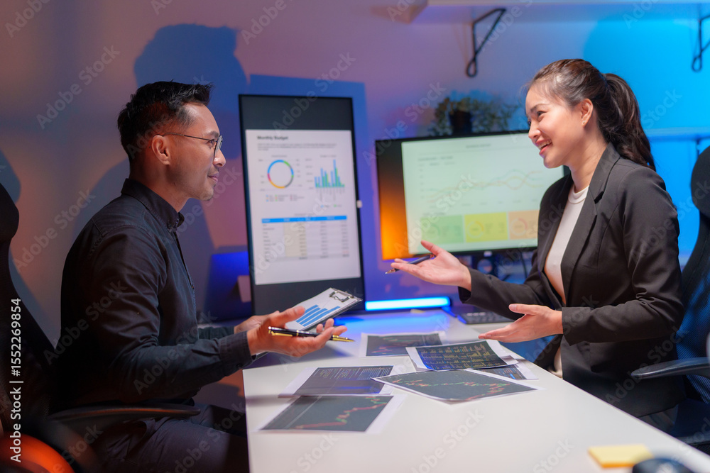 Business people discussing work in dark office. Cheerful businessman sdn businesswoman working late and talking in dark office. Cooperation concept Business people discussing work in dark office. Cheerful businessman sdn businesswoman working late and talking in dark office. Cooperation concept