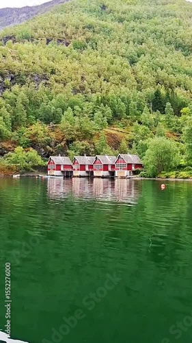 Traditional red boathouses reflecting in calm Flam fjord waters