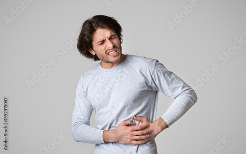 Liver pain. Guy holds hands on his side with torment facial expression