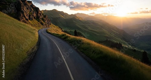 Scenic video of a winding road through mountainous terrain under a sunset sky with golden light illuminating the landscape