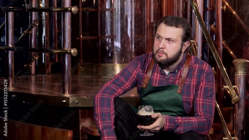 Relaxed brewer savoring his craft beer after a long day at the brewery Relaxed brewer savoring his craft beer after a long day at the brewery