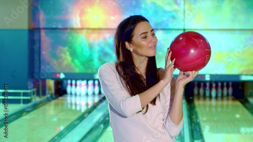 Confident girl poses with a bowling ball, ready to strike