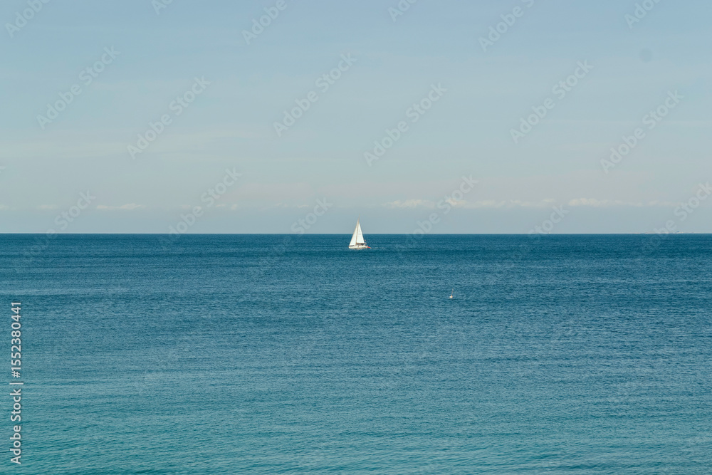 Fototapeta premium Minimalist Seascape with Lone Sailboat on the Horizon. Background, copy space