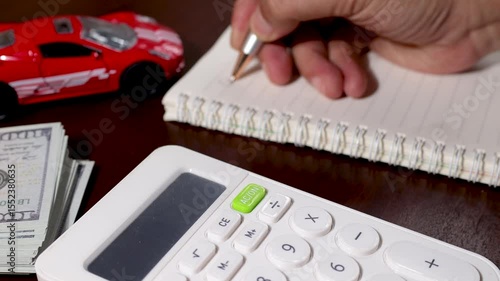A man calculates the total cost of buying a new car, including taxes and future maintenance, using a calculator at his desk. Ideal for illustrating financial decision-making and vehicle budgeting.