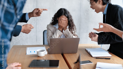 Workplace Conflict And Bullying. Aggressive Coworkers Yelling At Victimized Businesswoman Sitting At Desk In Modern Office. Corporate Communication Problem, Quarrels And Bad Attitude At Work