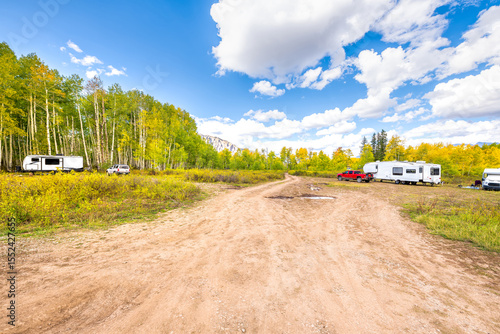 Kebler Pass, Colorado scenic dirt road to cars in campground trailhead parking in autumn fall through aspen trees golden yellow colorful forest