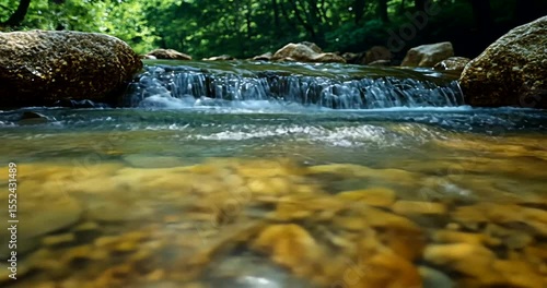 Tranquil stream with pebbles and gentle waterfall