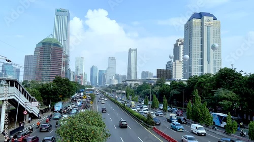 4k Video Busy Jakarta Urban Skyline with Highrise Buildings, City Traffic, Buses, and Modern Skyscrapers Under Clear Blue Sky