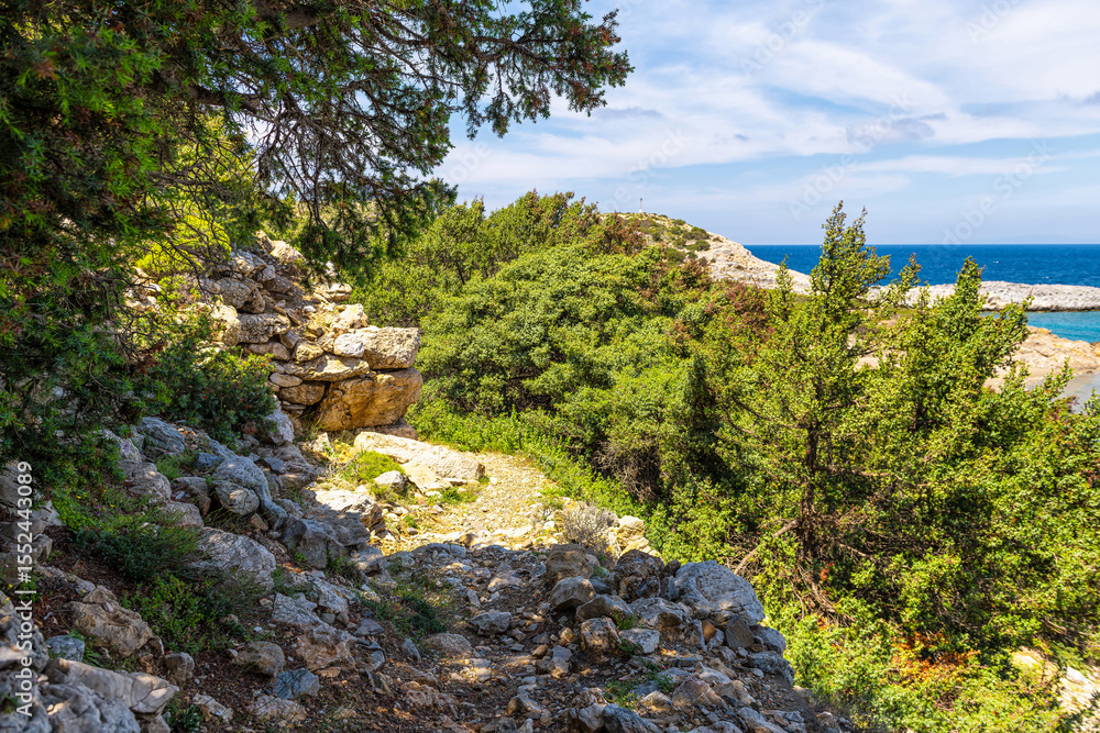 Stone rock wall at Ikaria island Greece trail footpath in Greek longevity blue zone by Drakano Tower with St George beach and nobody Stone rock wall at Ikaria island Greece trail footpath in Greek longevity blue zone by Drakano Tower with St George beach and nobody