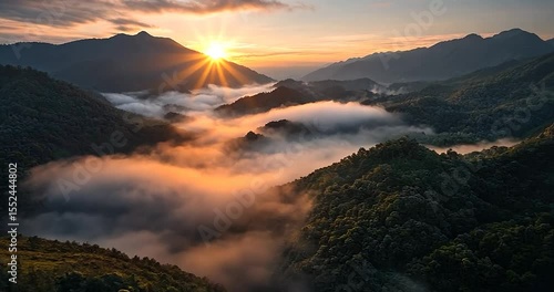 Aerial video shows a mountain range shrouded in early morning mist bathed in golden sunrise light
