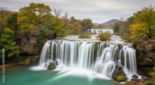 Scenic cascade in a lush forest with vibrant autumn foliage and misty spray