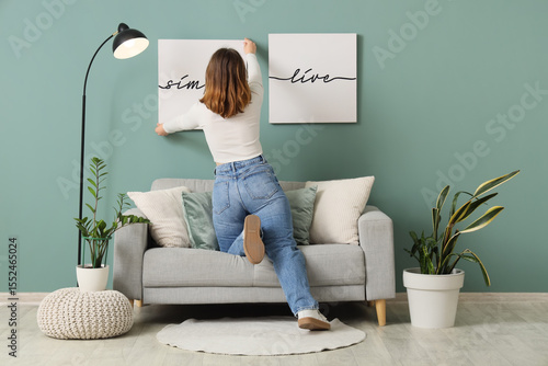 Young woman hanging picture...