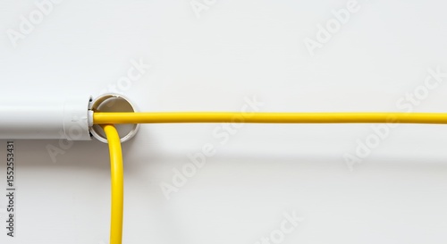 Yellow electrical cable connected to white wall outlet