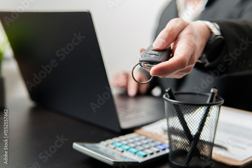 Car salesman is giving car key to customer after signing contract in dealership office