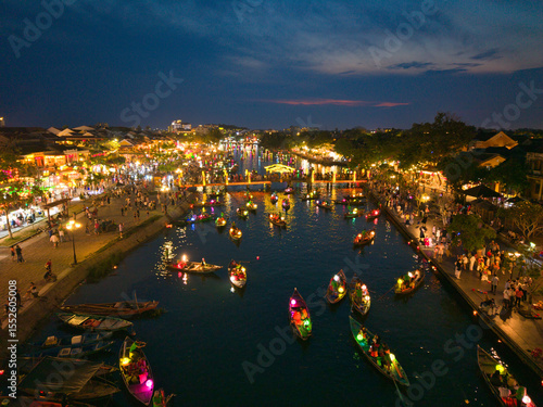 Wallpaper Mural  Aerial shot of Hoi An at night with lanterns floating on the river, tourists walking the streets, and boats creating a festive atmosphere. Great for cultural and travel media Torontodigital.ca