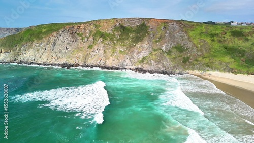 Witness the stunning aerial view showcasing the turquoise ocean waves dramatically crashing against rocky cliffs