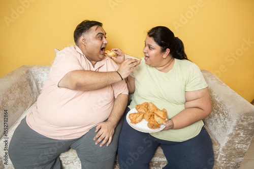 Vászonkép Hungary overweight fat indian couple eating unhealthy samosa junk food together