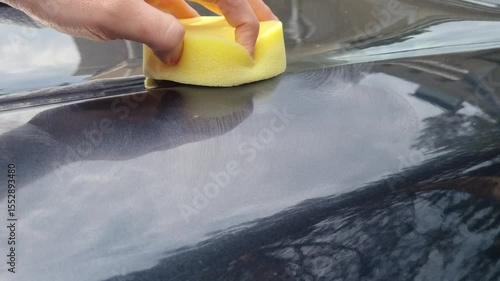 professional service man polishing and detailing on a car body, professional workman waxing a wax on a vehicle. Car wash service.