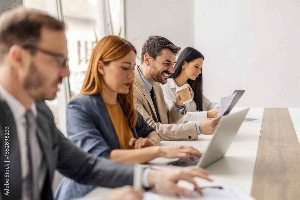 Fototapeta premium Selective focus on a businessman drinking coffee and doing through paperwork while sitting with leadership team at corporate office.