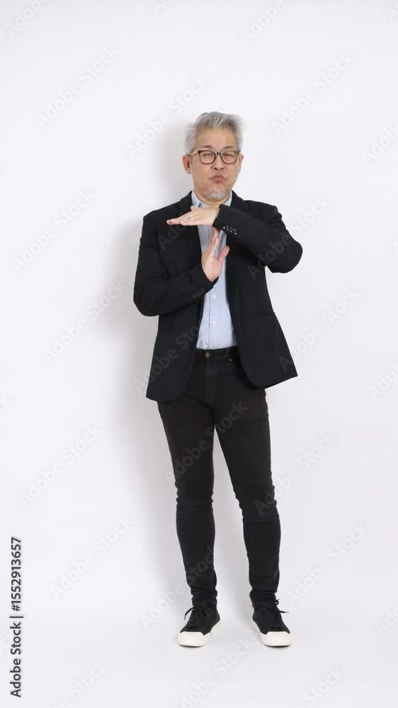 This is a portrait of an East Asian businessman with gray hair and glasses, dressed in a black suit, standing against a white background. This is a portrait of an East Asian businessman with gray hair and glasses, dressed in a black suit, standing against a white background.