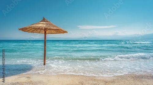 Straw beach umbrella positioned in front of a calm blue sea under a bright sky
