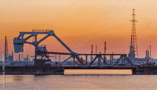 Riveted bascule bridge during a sunset with harbor activity on the background, Port of Antwerp, Belgium.