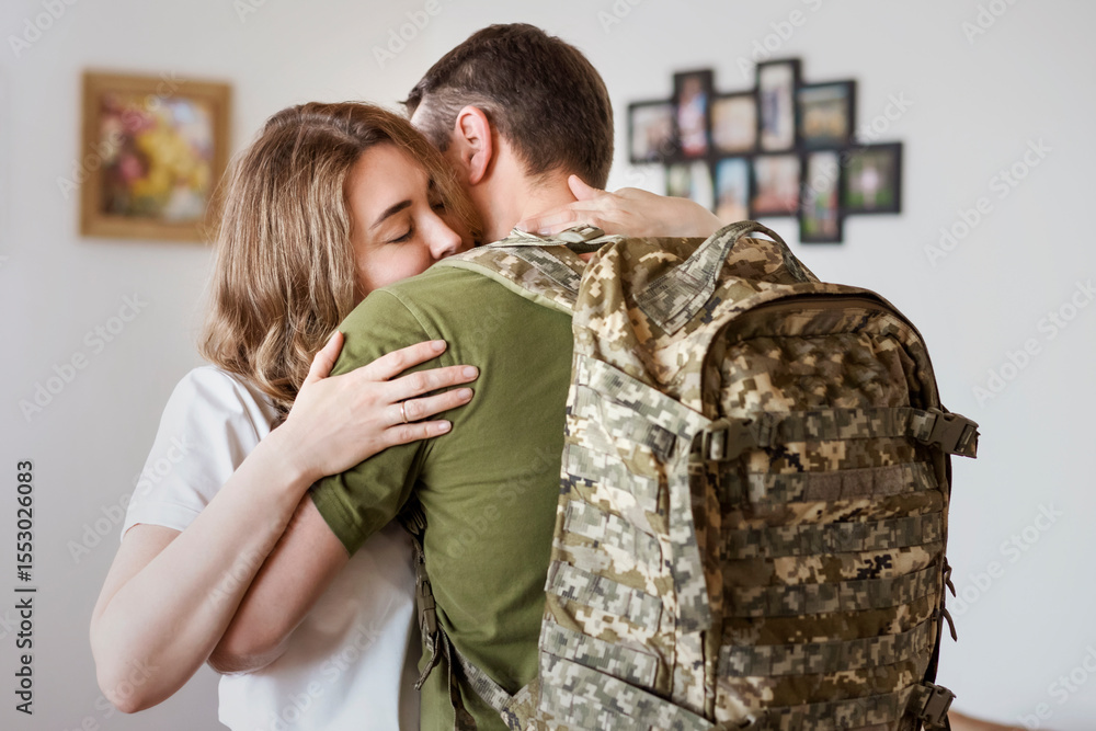 Fototapeta premium Military Ukrainian Soldier Embraces Wife Before Leaving for Duty. Sad Farewell Between Military Man and His Wife at Home