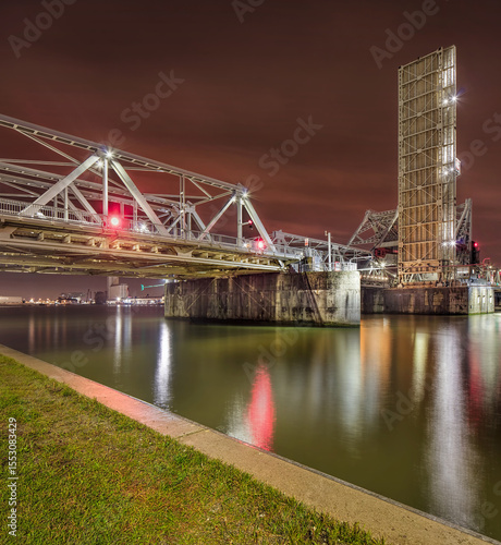 Massive illuminated bridge at night, reflected in the river, Port of Antwerp, Belgium