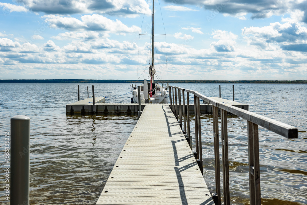 Fototapeta premium Sailing boats for rent moored to a pier in a yacht marina on lake. Vacations, recreational sailing, cruise.