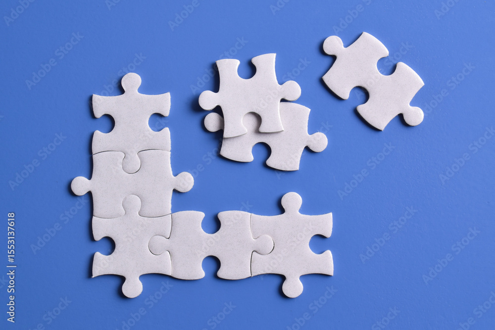 White puzzle pieces on blue background, top view White puzzle pieces on blue background, top view