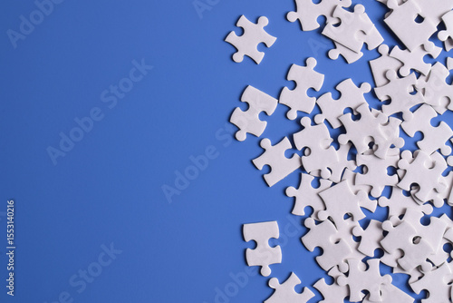 White puzzle pieces on blue background, top view. Space for text