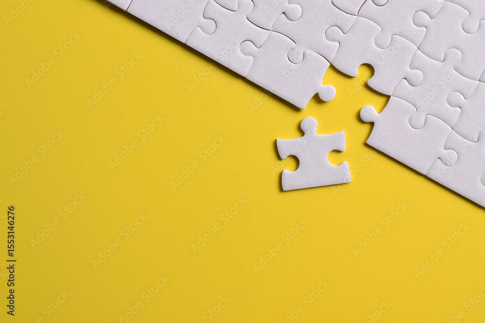 Obraz premium White puzzle pieces on yellow background. Flat lay. Top view