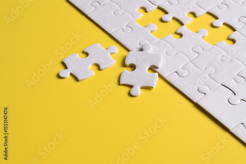 White puzzle with missing piece on yellow background. Top view