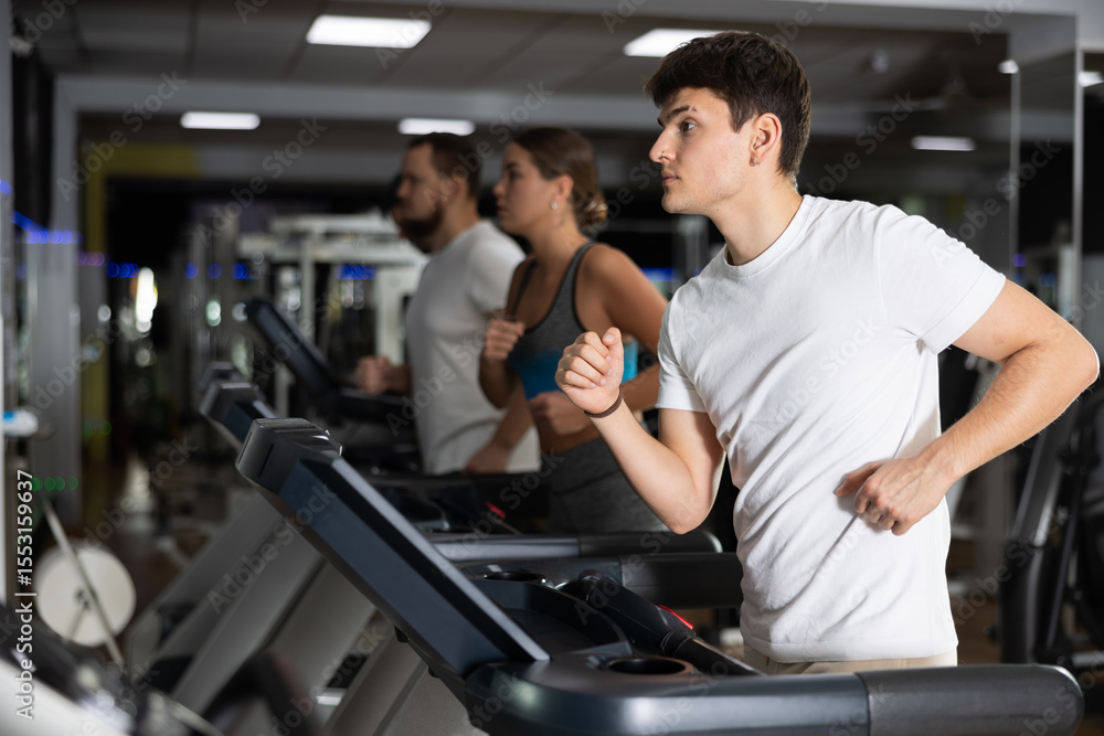Guy hardly perform exercise on treadmill and running during fitness class. Fitness equipment, visitors engaged in physical task during training and perform brisk walking on treadmill Guy hardly perform exercise on treadmill and running during fitness class. Fitness equipment, visitors engaged in physical task during training and perform brisk walking on treadmill