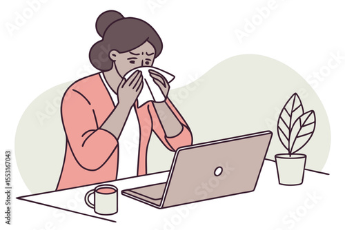 The woman pauses her work to sneeze into a tissue, looking visibly annoyed by her condition.