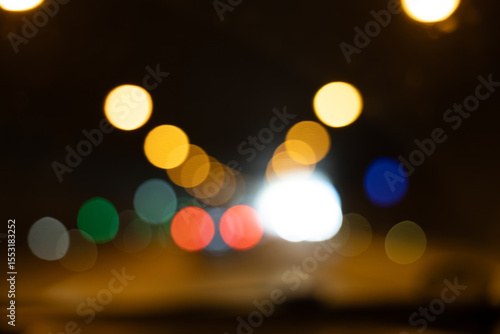 Colorful blurry light circles on a dark background, symbolizing tunnel exit with car lights. Abstract vision of driving fatigue and long road trips at night