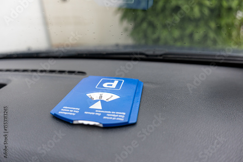 Blue parking disc behind a car windshield with rain drops on glass. Urban detail, rainy day, time-limited parking concept in a real-life scene