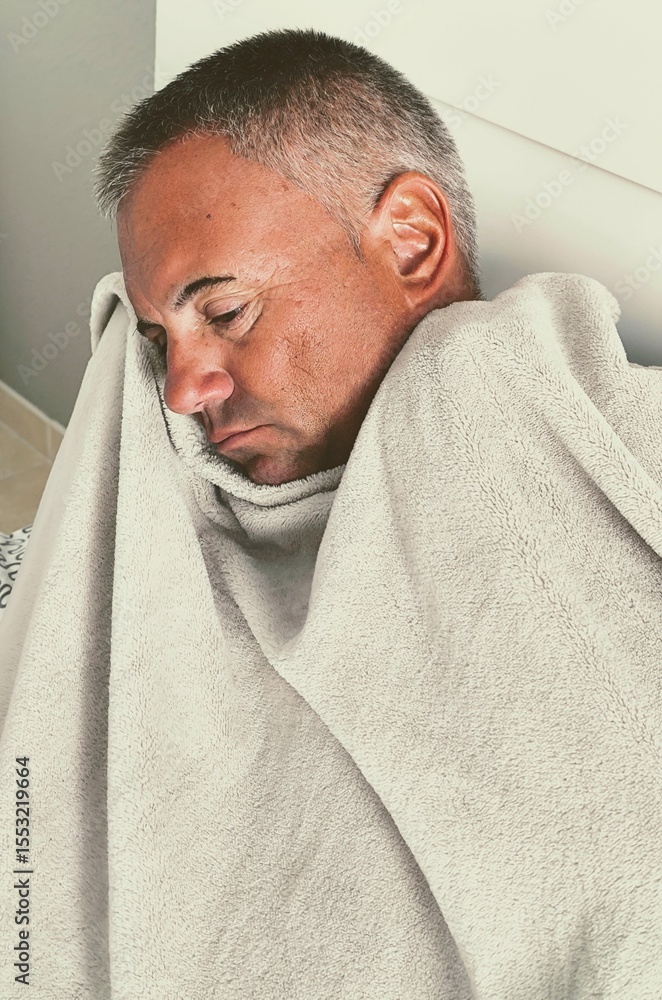 Fototapeta premium Man in bed with blanket. Sick adult in bed wrapped in blanket. Flu man depressed in bed, rolled up under blankets. Cold male with stomach virus and joint pain. Winter, cold, illness, fever, flu, virus