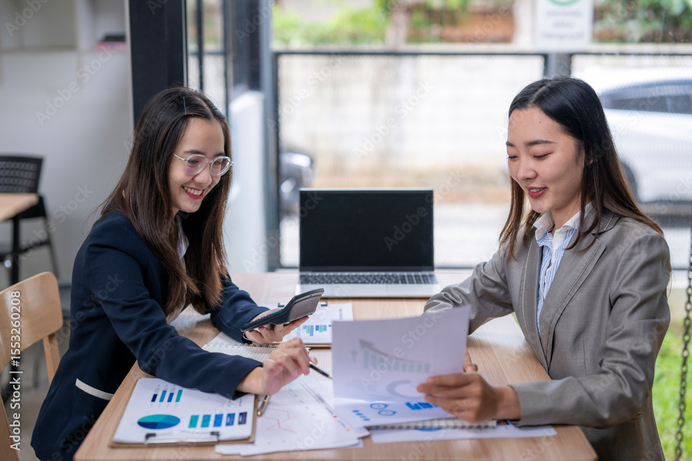 Obraz premium Businesswomen working together analyzing charts and financial data in office