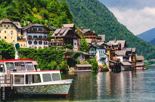 Hallstadt in Austria. A boat is docked in front of a house. The house is surrounded by trees and has a green roof