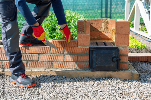 Foto man building bricks barbeque at the backyard.