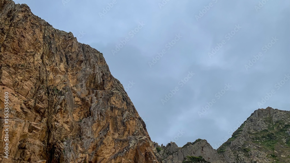 Rugged cliffs ascend majestically under a brooding sky, hinting at ancient tales of Earth Day and Fengari's Night