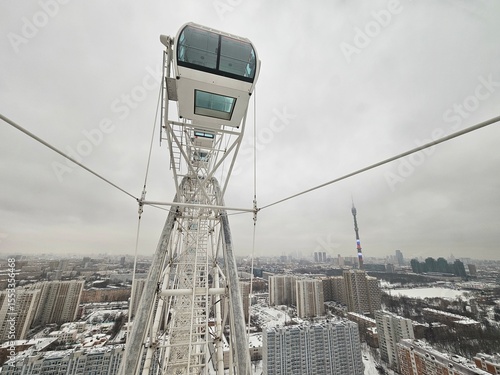 Photography Large Ferris wheel with a glass top is in the middle of a city