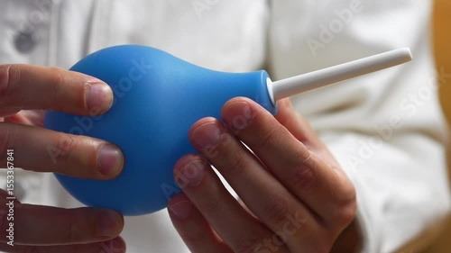 Blue enema in the hands of a doctor before use in a hospital.
Stomach and intestinal problems.
Treatment of constipation with an enema.
Topic of medicine