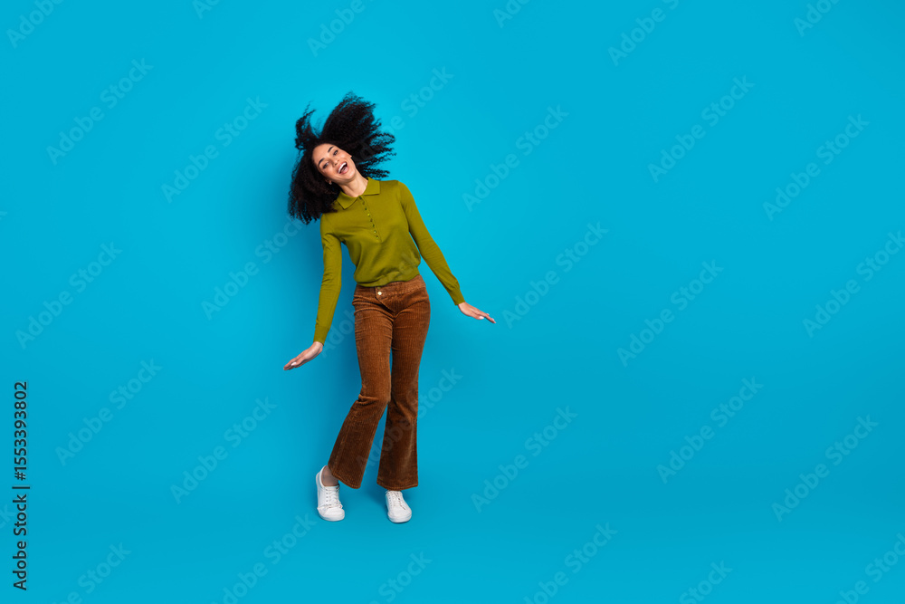 Obraz premium Young charming woman joyfully posing against a vivid blue backdrop wearing trendy casual attire with a cheerful attitude