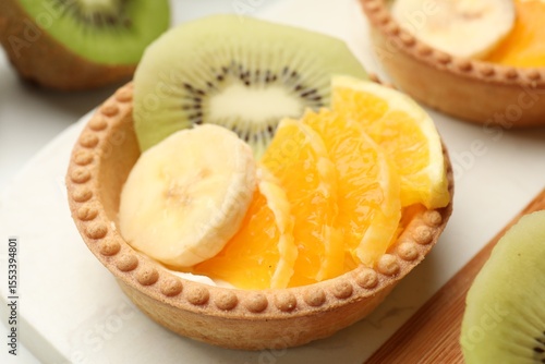 Tartlets with fruits on table, closeup. Delicious dessert