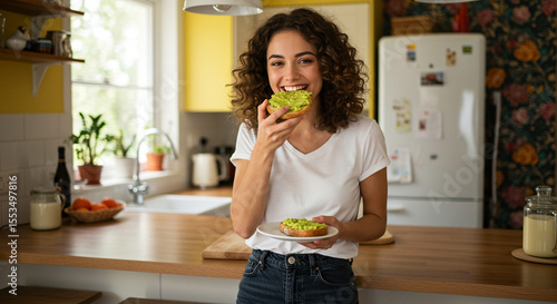 Woman standing in a cozy kitchen taking a bite of avocado toast