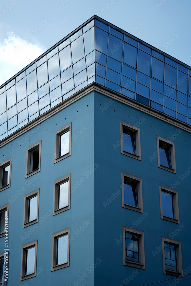 Building facade close-up. Blue wall exterior. Multiple square windows. Sky background.
Building facade close-up. Blue wall exterior. Multiple square windows. Sky background.