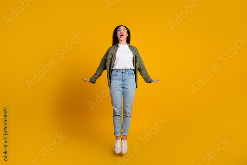 Cheerful young woman wearing casual fashion poses joyfully against a yellow background