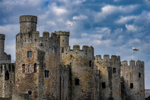 Medieval Conwy Castle, a UNESCO World Heritage site against blue sky, with the Welsh flag flying from one of its towers